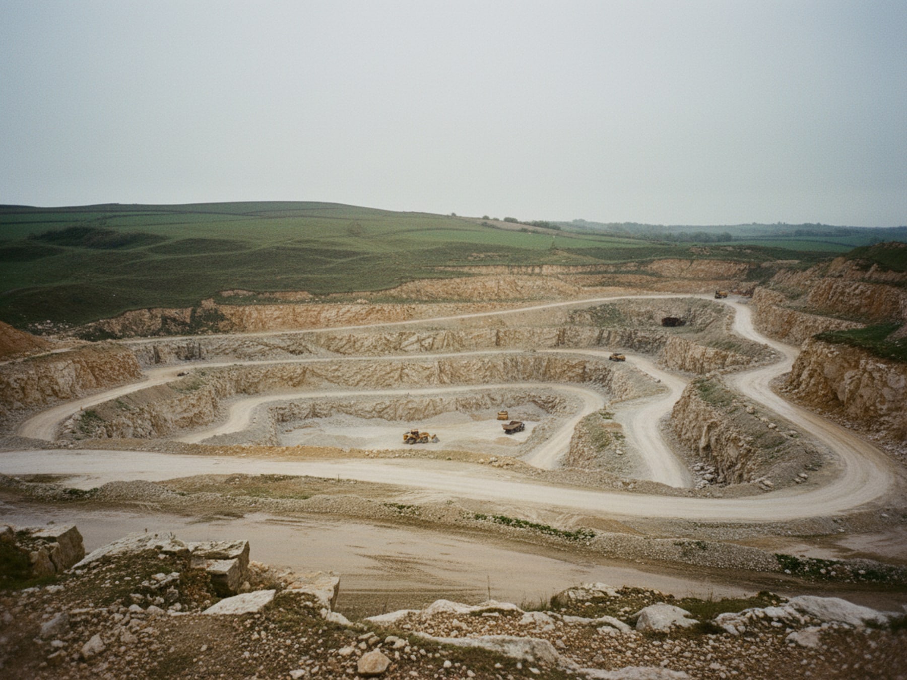 Open terraced quarry cut into hillside under overcast sky
