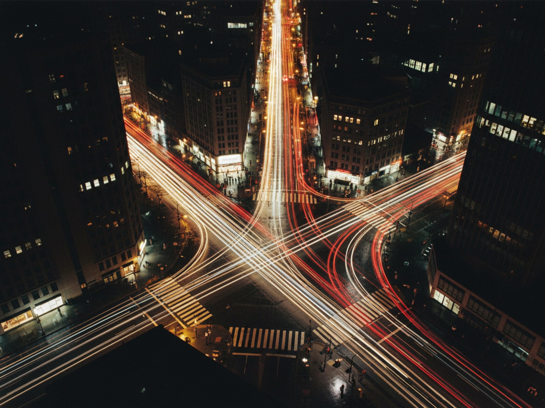 Elevated view of a dense city intersection with light trails at dusk